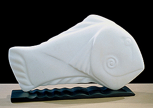 fish carved from Yule marble with a spiraled smile, sitting ontop of a rippling piece of slate