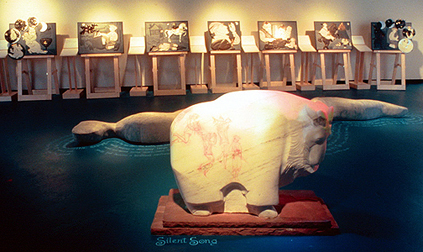 tactile art exhibit , fairy tale in slate background, carved mable goat in foreground